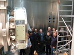 The photograph shows the participants at the meeting inside the shielding in front of the main insulator of the 60 kV accelerator. 